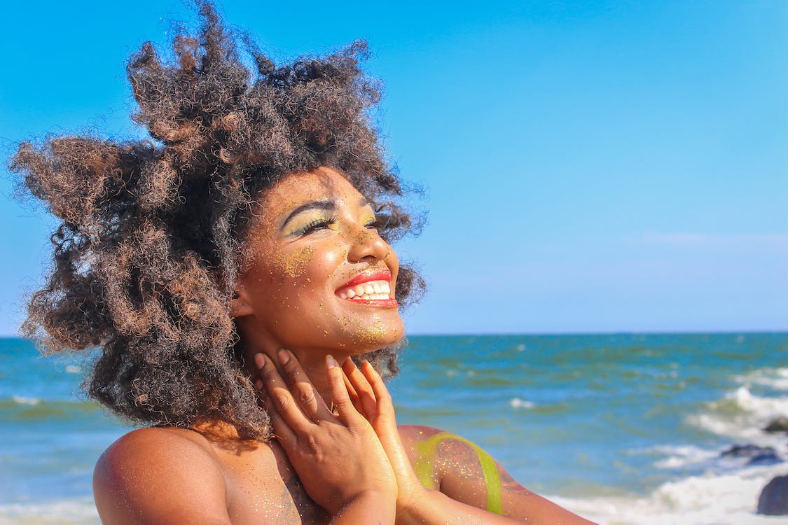 black beauty with afro gazing at the sun while at the beach